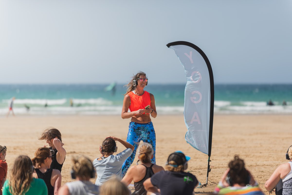 Alicia leading a silent-disco beach yoga session